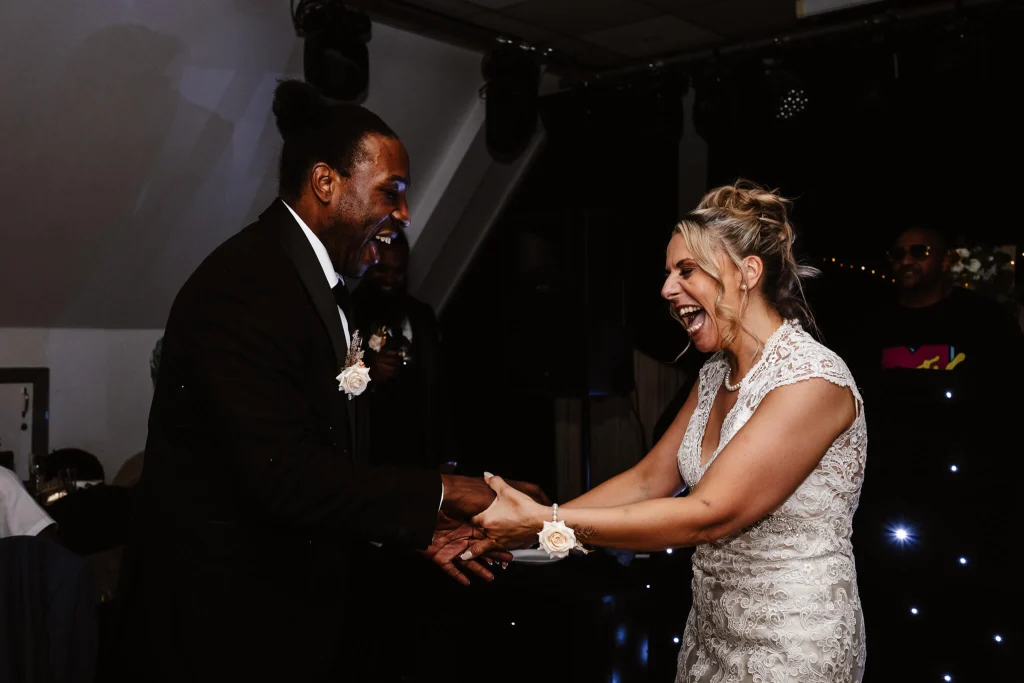Bride and groom laughing together during their first dance at High Wycombe Cricket Club wedding reception in Buckinghamshire.