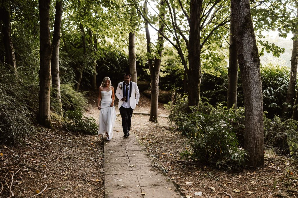 Bride and groom walking through woodland at Hellidon Lakes Hotel & Resort